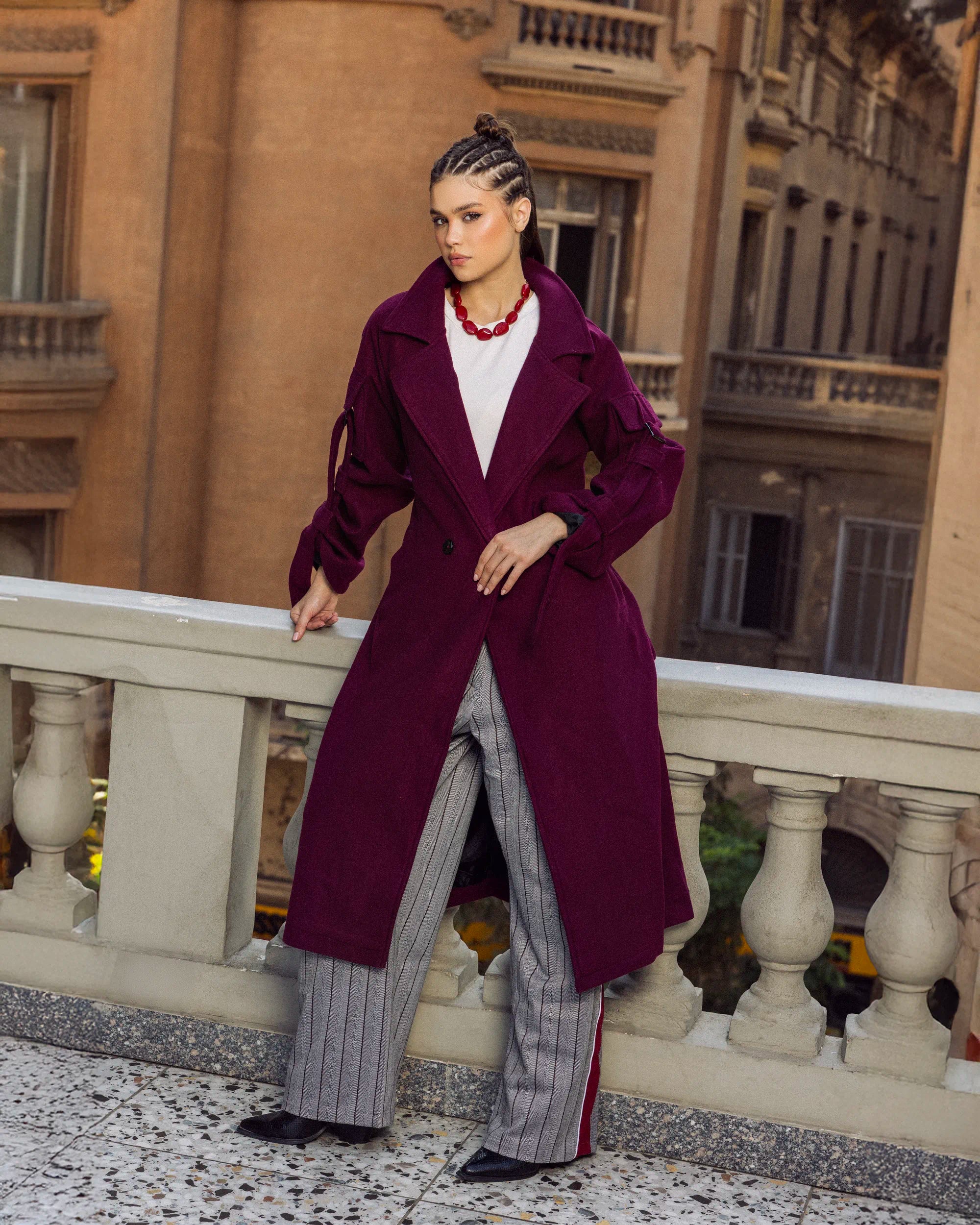 “Model wearing the burgundy Bound Coat highlighting its structured wool silhouette and minimal belt.”