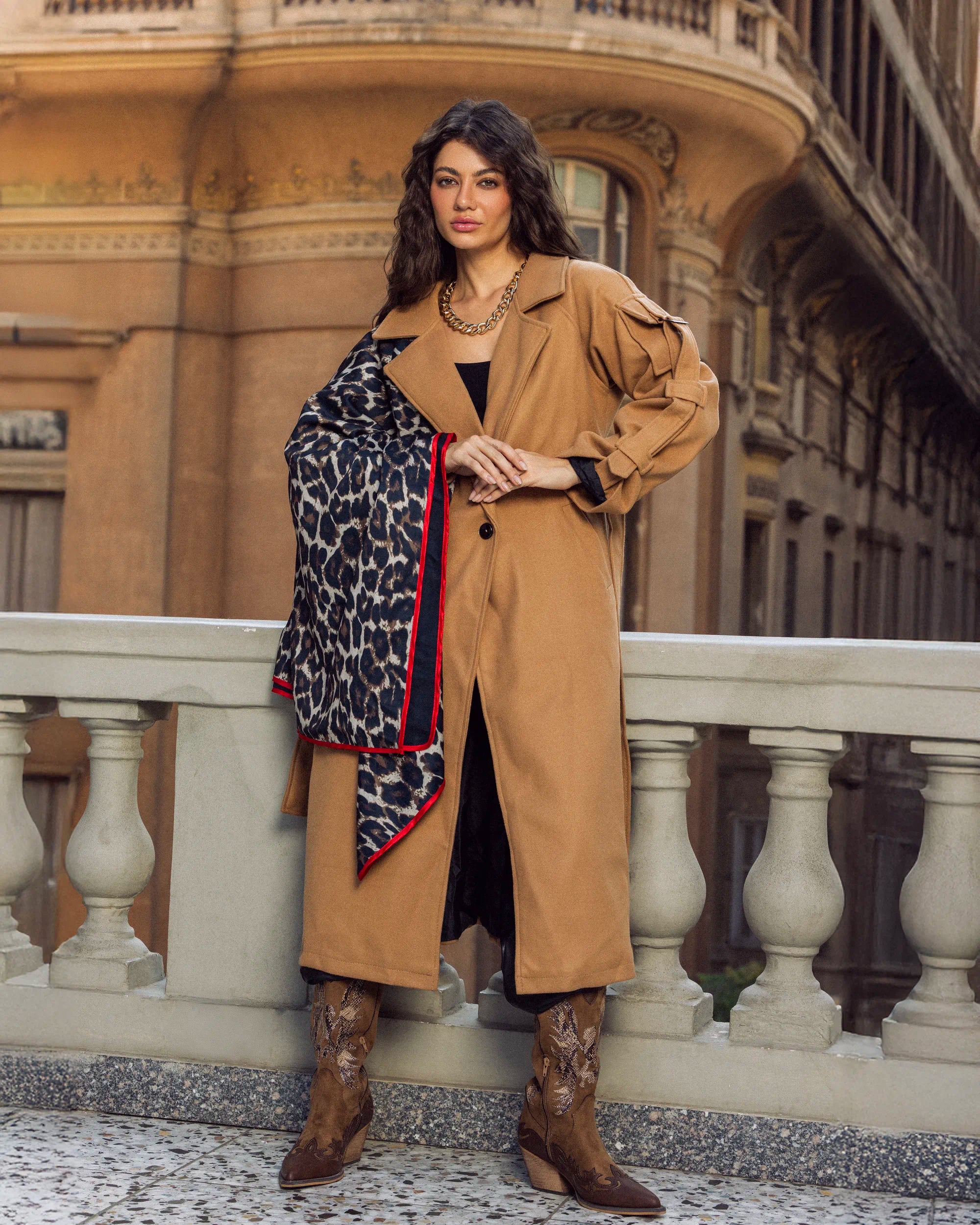 “Model wearing the beige Bound Coat in a full-body balcony pose showing the tailored wool silhouette.”