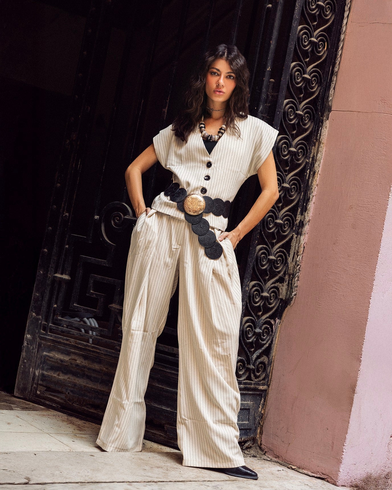 Woman in a stylish outfit standing in front of a decorative door.