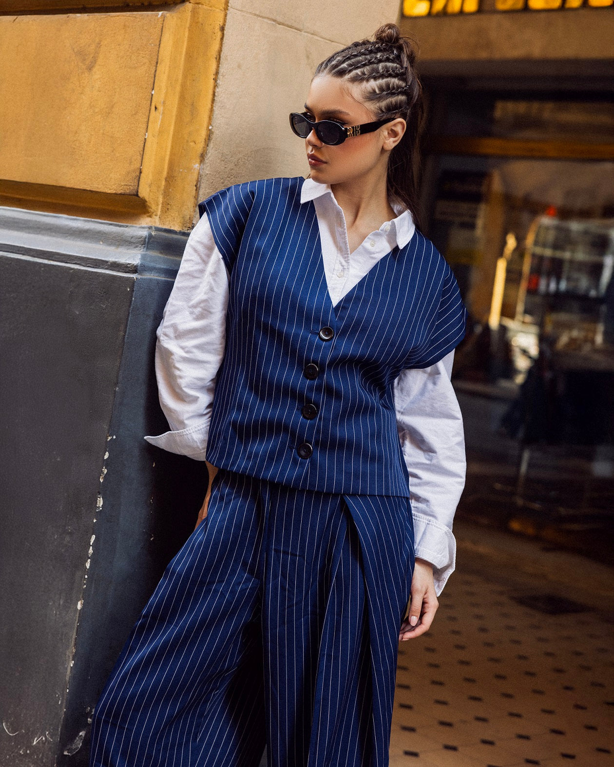 Woman wearing a blue pinstripe suit with a white shirt, standing in an urban setting.