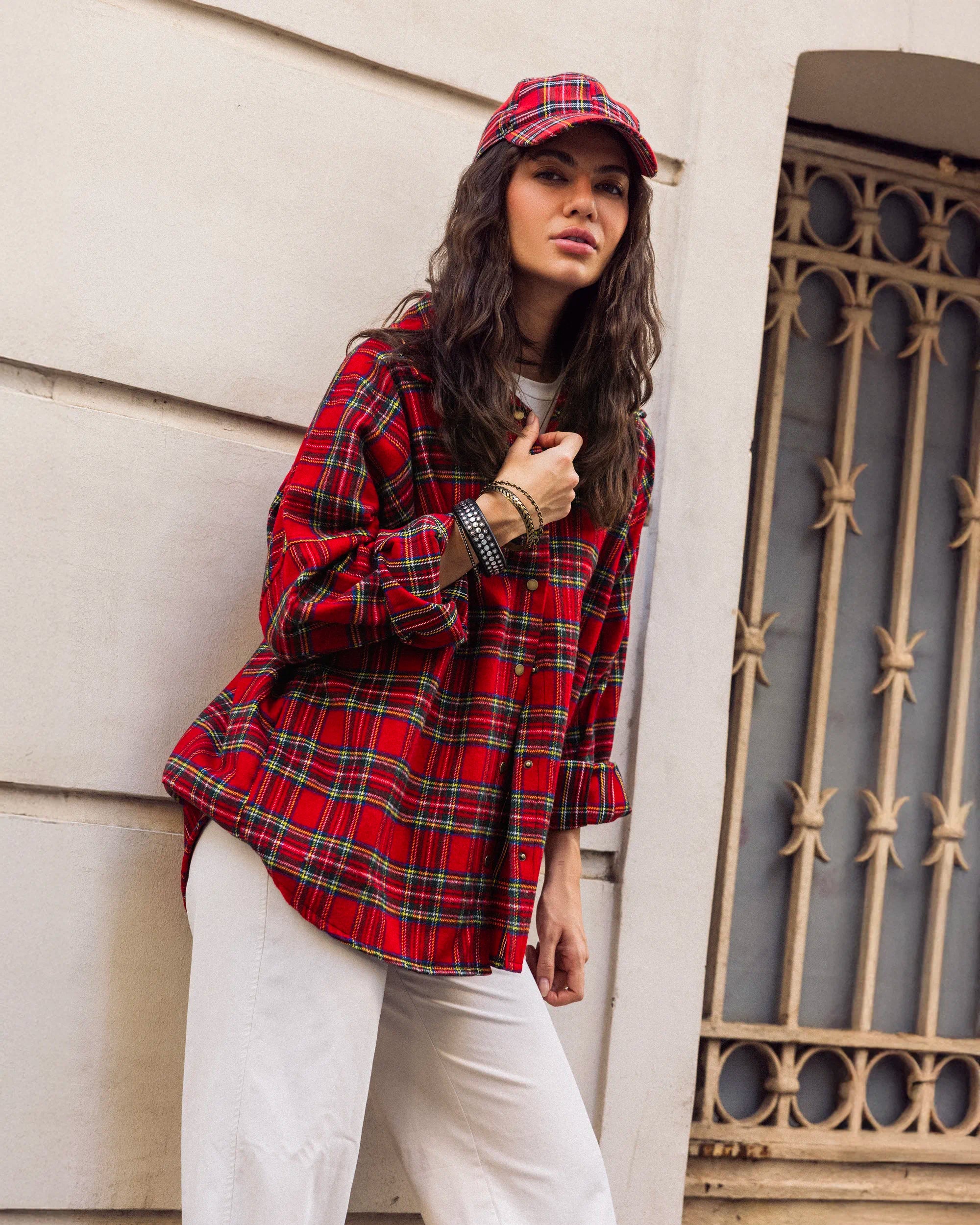“Model sitting while wearing the dark plaid Griddy Shirt, highlighting its oversized wool texture and winter feel.”