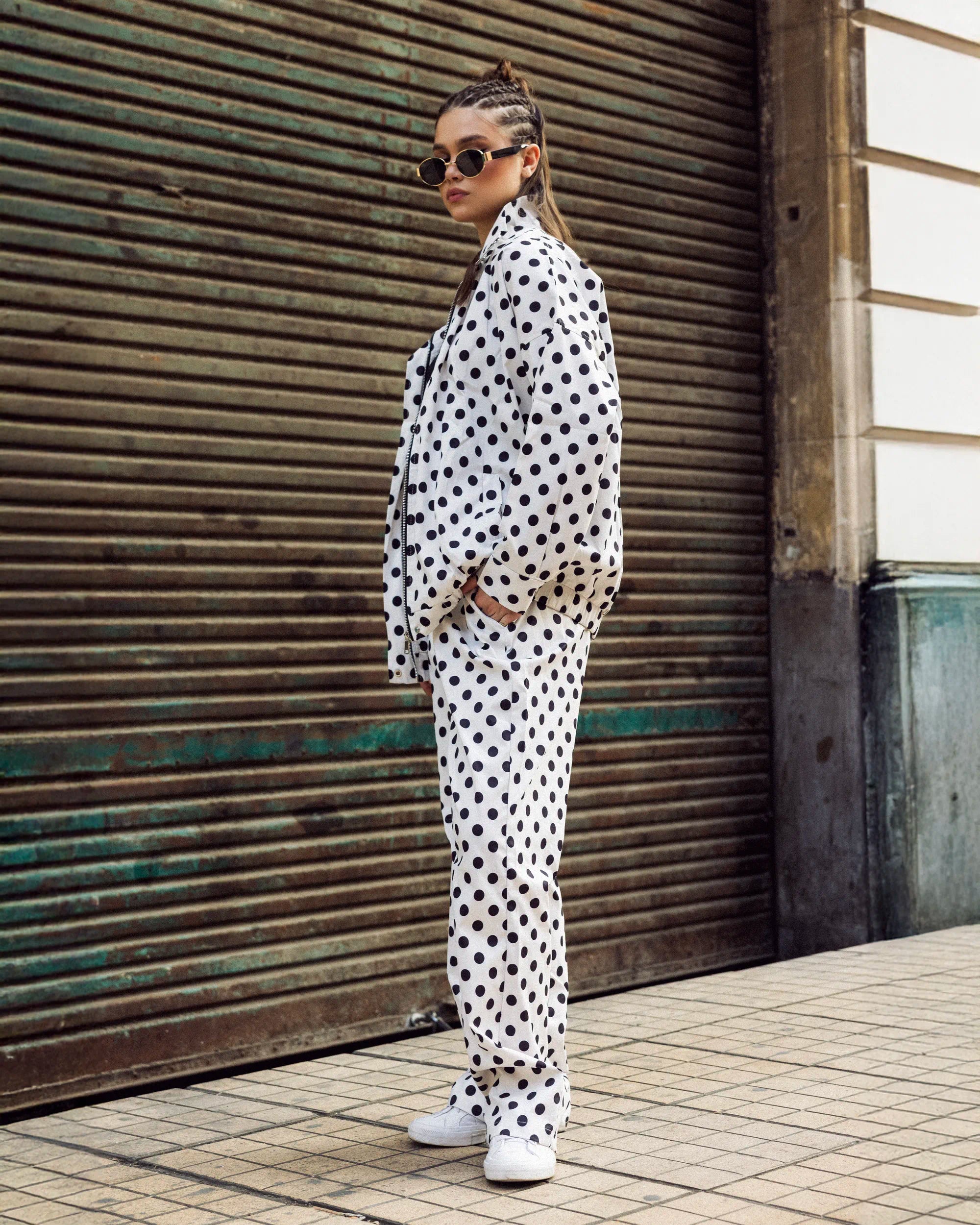 “Model wearing the white Polka Set in a relaxed standing pose, showing the bold polka-dot pattern and lightweight waterproof finish.”