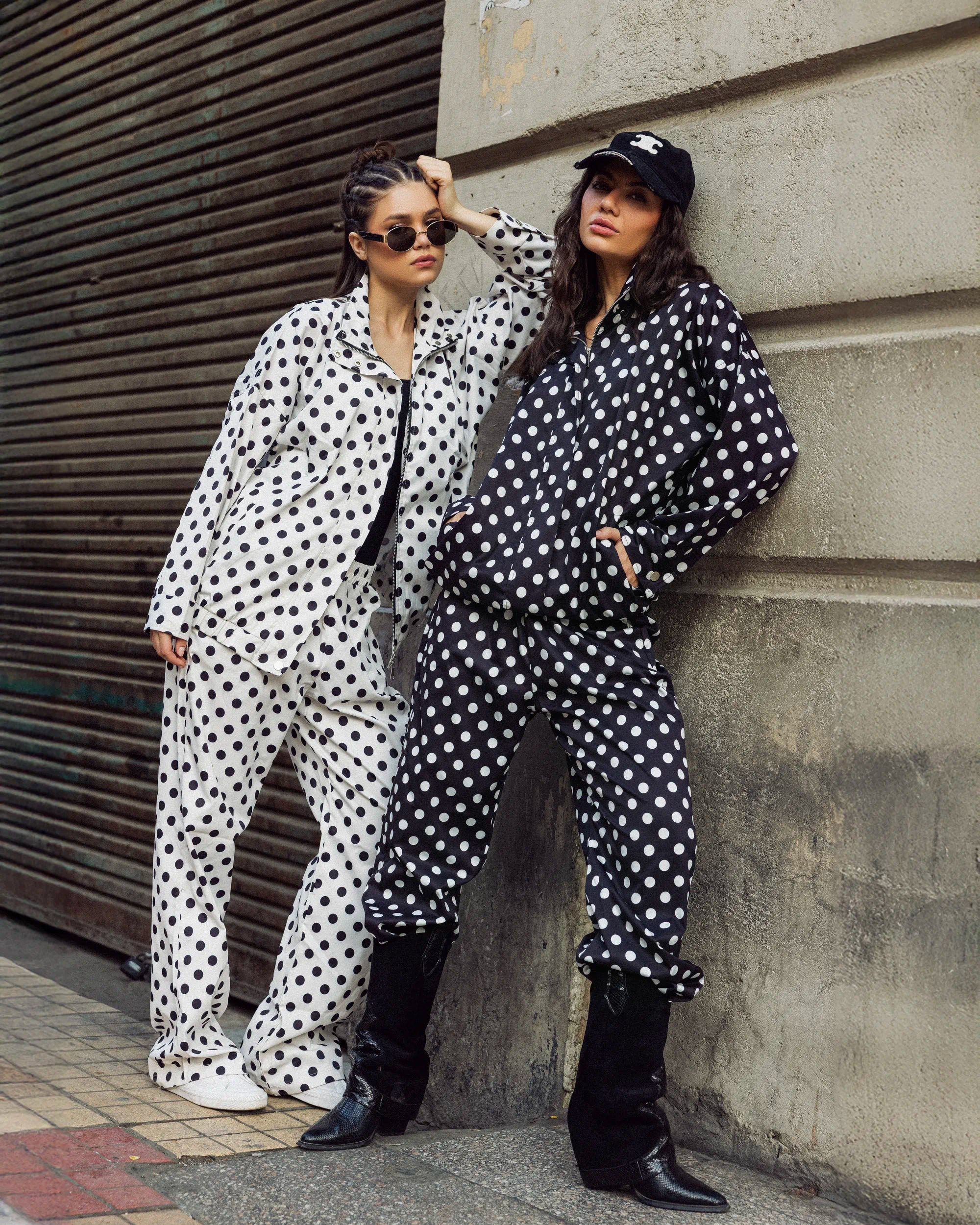 “Two models wearing the Polka Set in black and white, showcasing the relaxed waterproof gabardine fit with bold polka dots.”