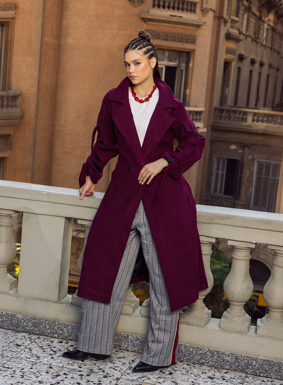 “Model wearing the black Bound Coat, a wool tailored winter coat with a subtle belt, photographed in a front-standing outdoor pose.”