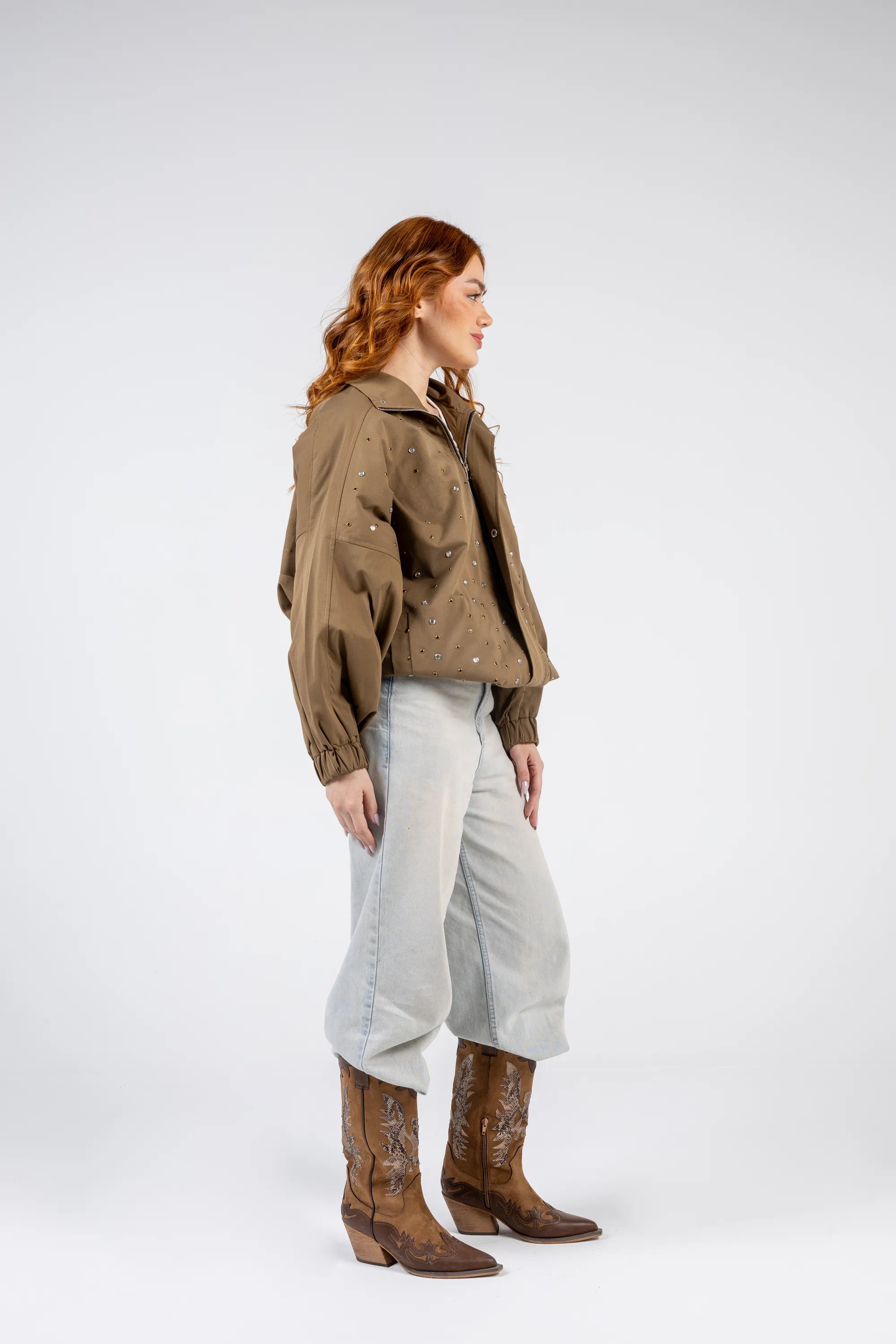 Person wearing a brown jacket, light gray pants, and brown boots on a white background