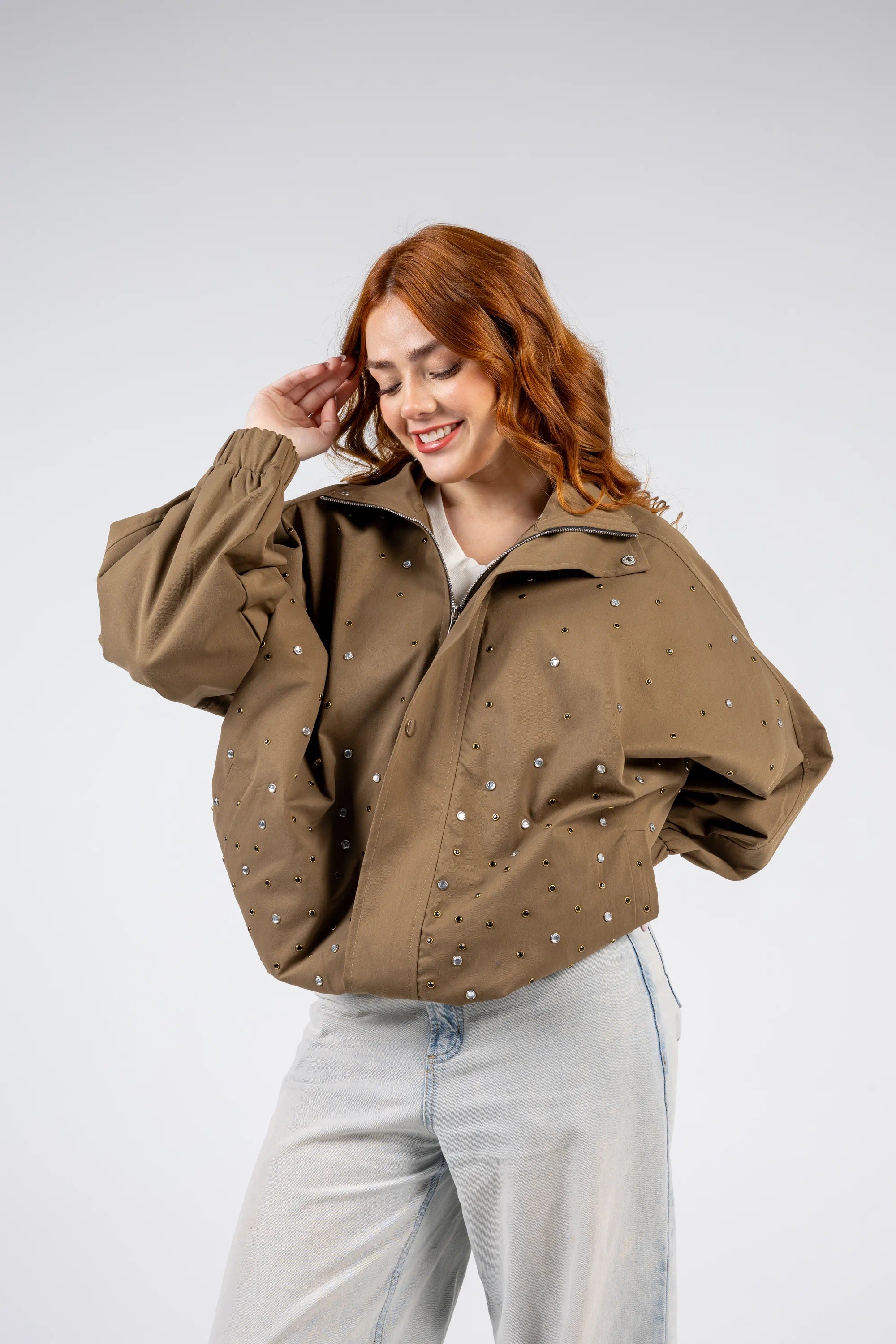 Woman wearing a brown jacket with pearl embellishments on a white background