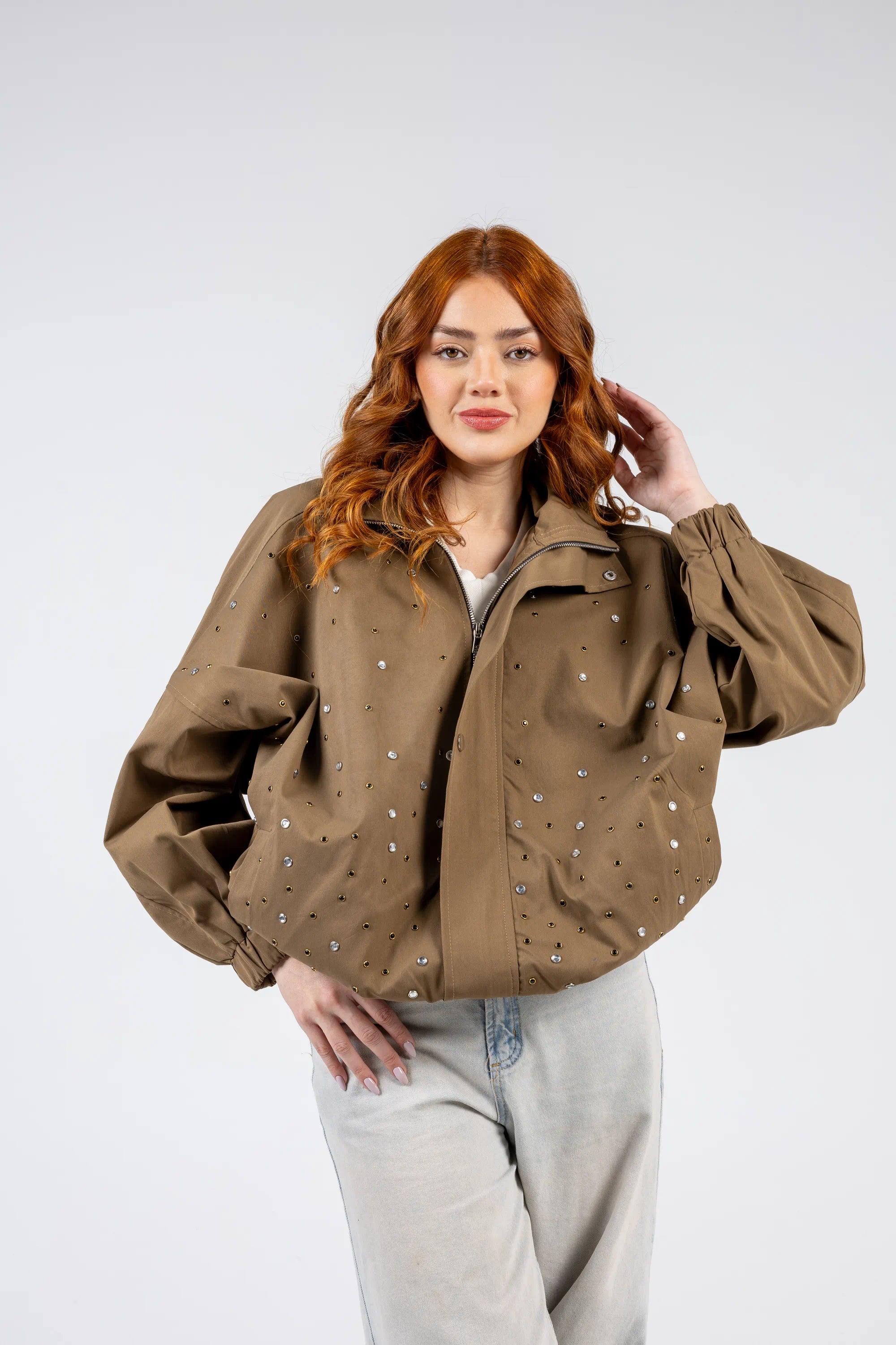 Woman wearing a brown jacket with pearl embellishments on a white background