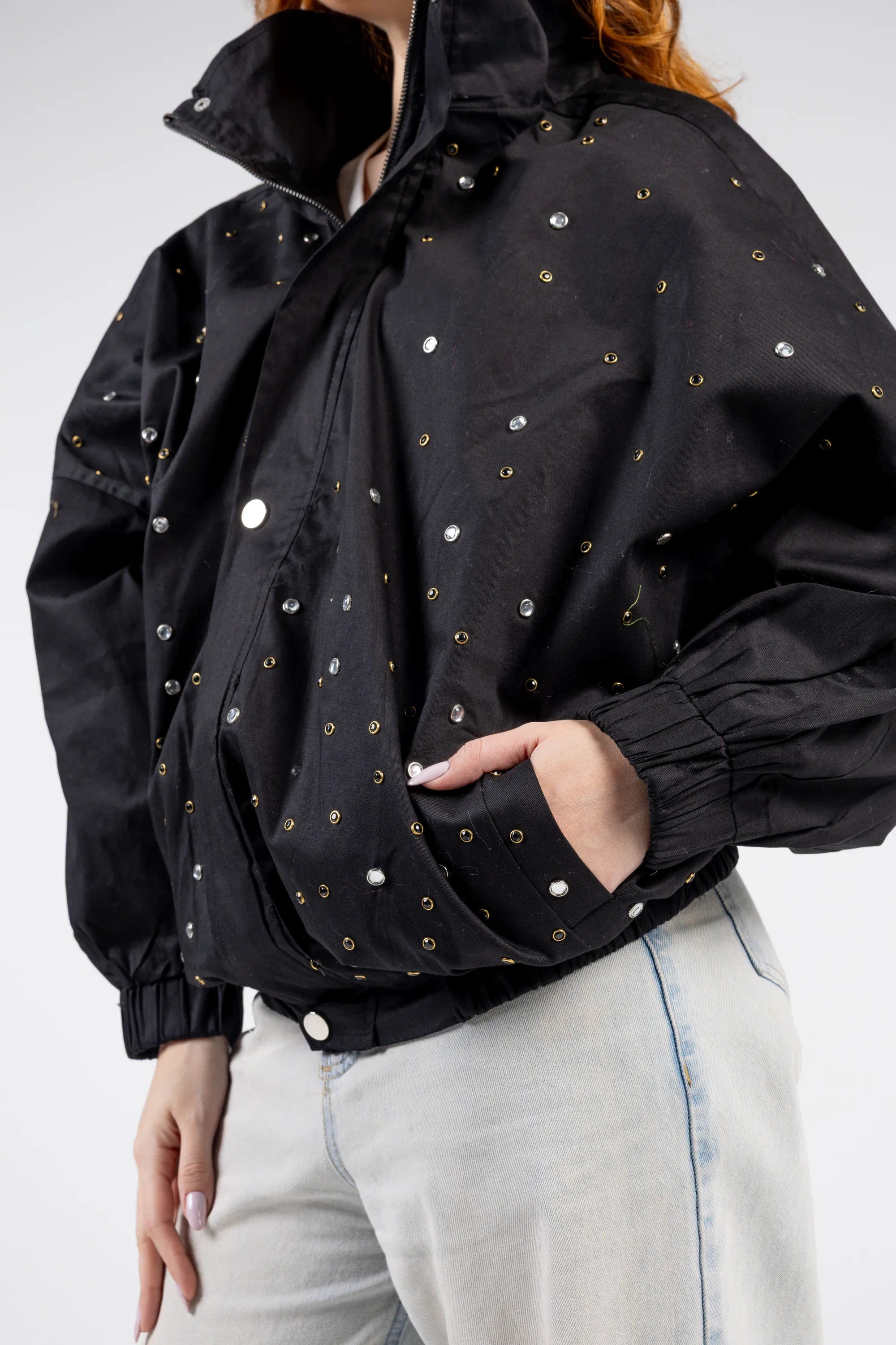 Person wearing a black jacket with gold studs on a white background
