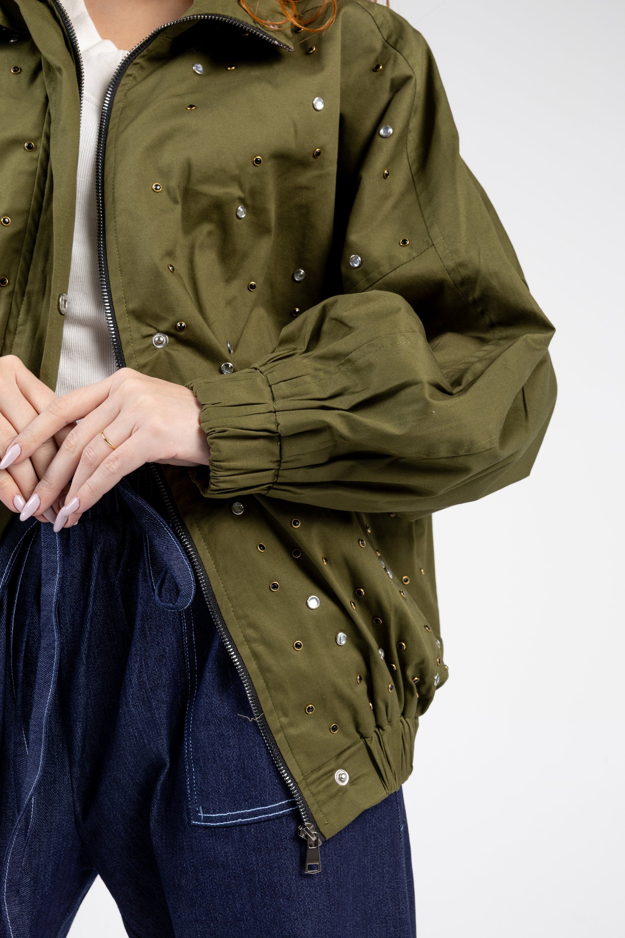 Person wearing a green jacket with decorative buttons on a white background