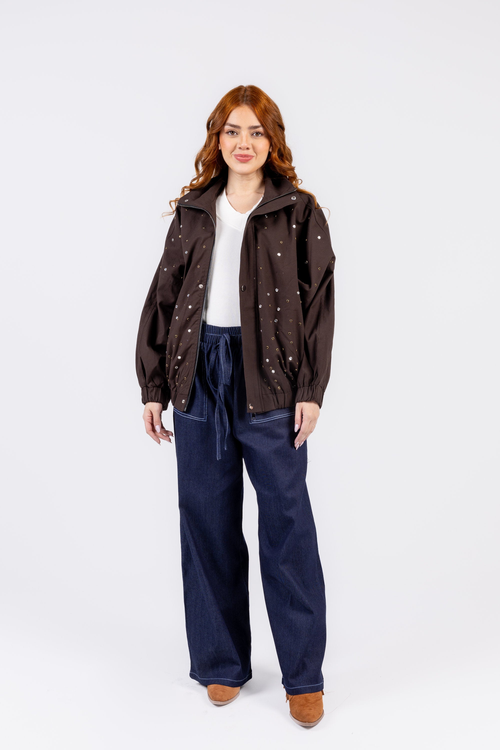 Woman wearing a brown jacket and navy pants on a white background