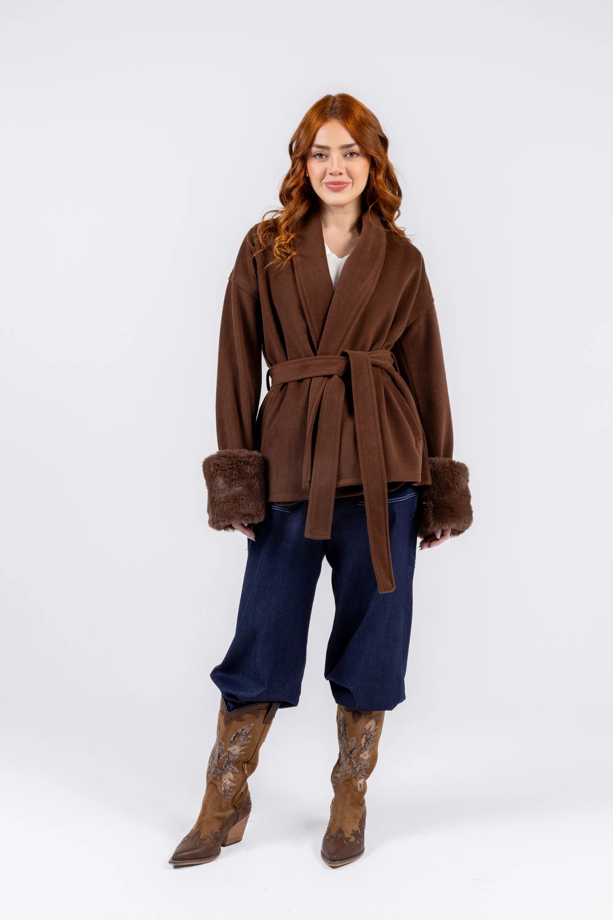 Woman wearing a brown coat with fur trim on a white background