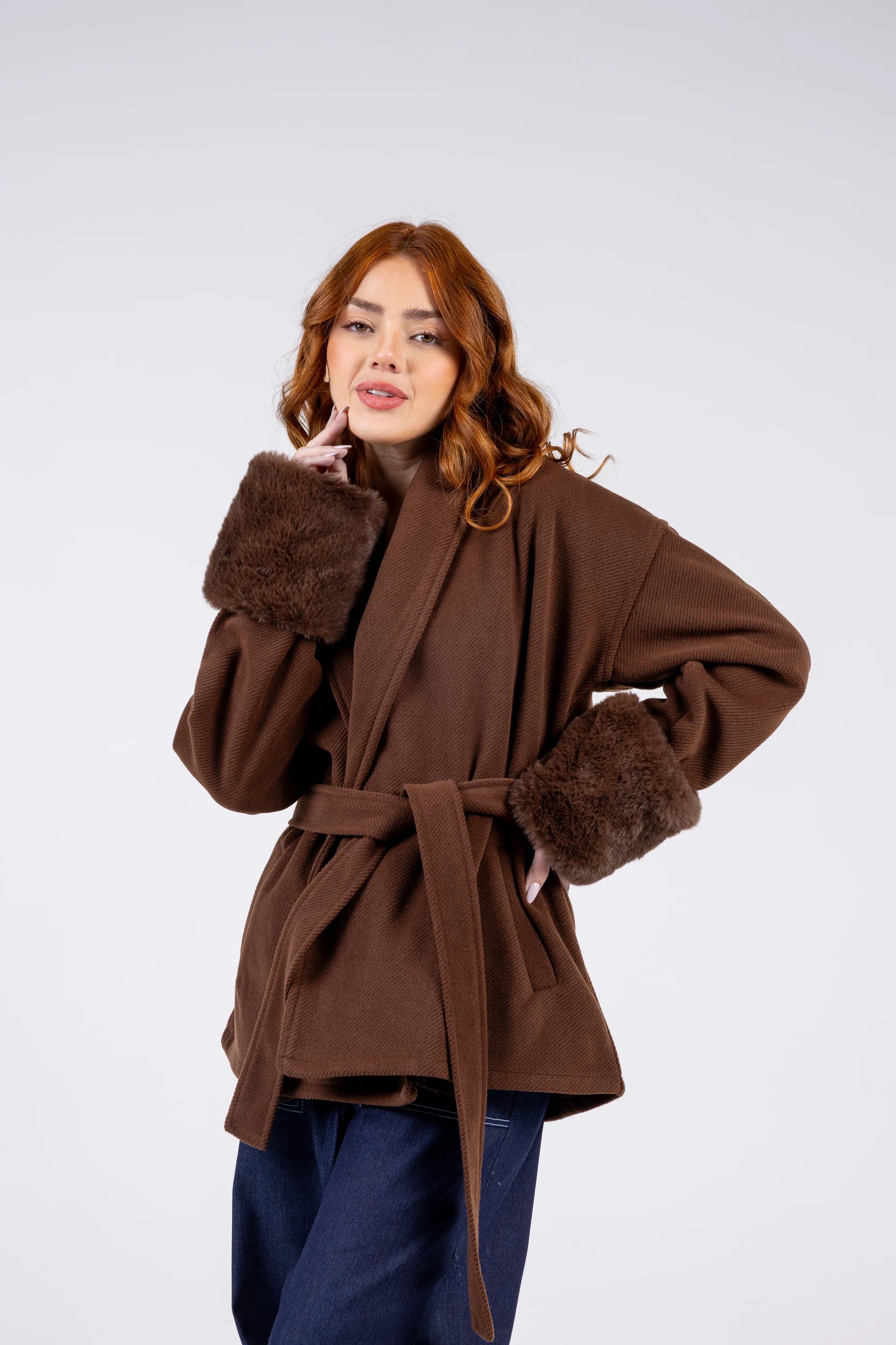 Woman wearing a brown coat with fur trim on a white background