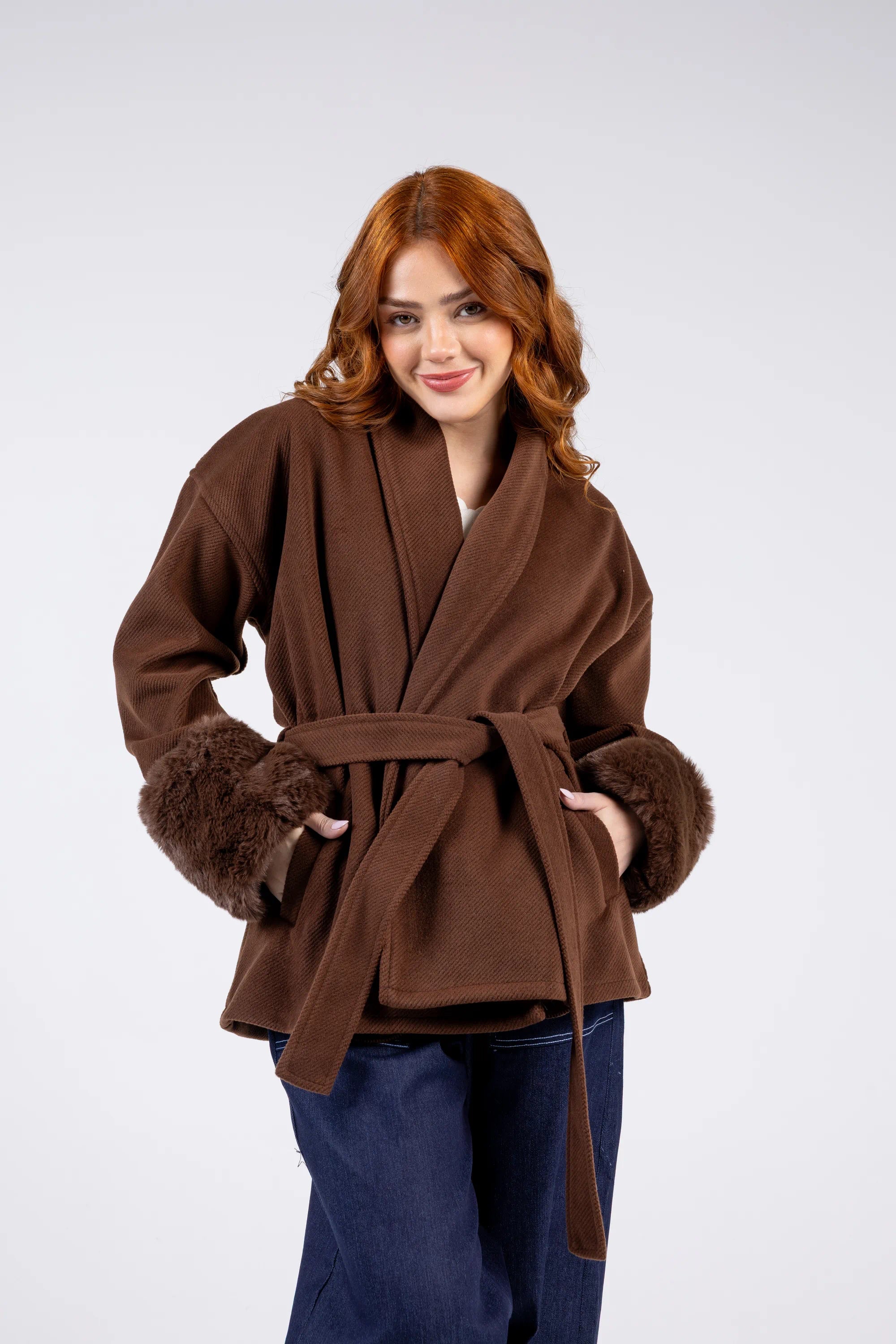 Woman wearing a brown coat with fur trim on a white background