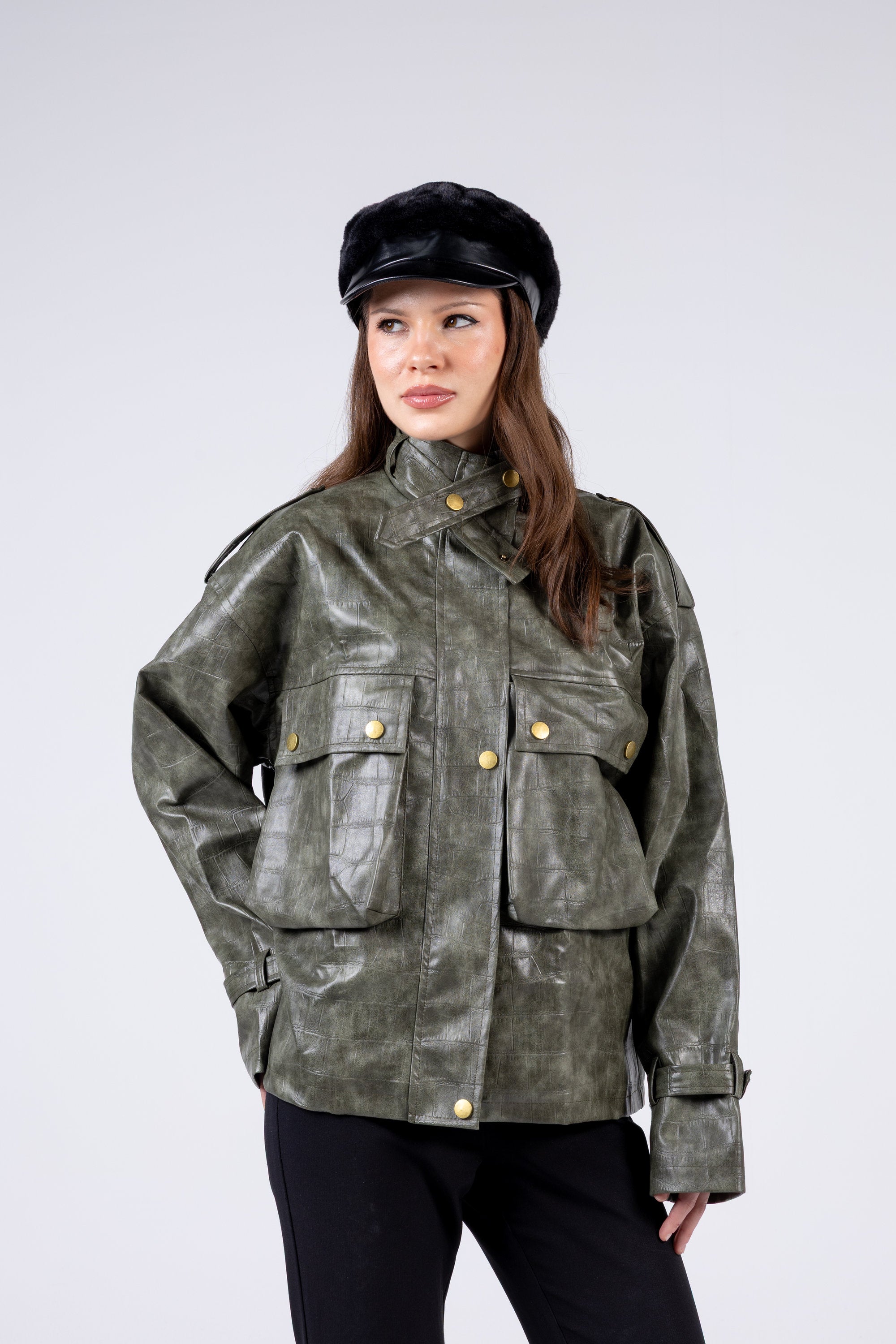 Woman wearing a green leather jacket and black cap on a white background