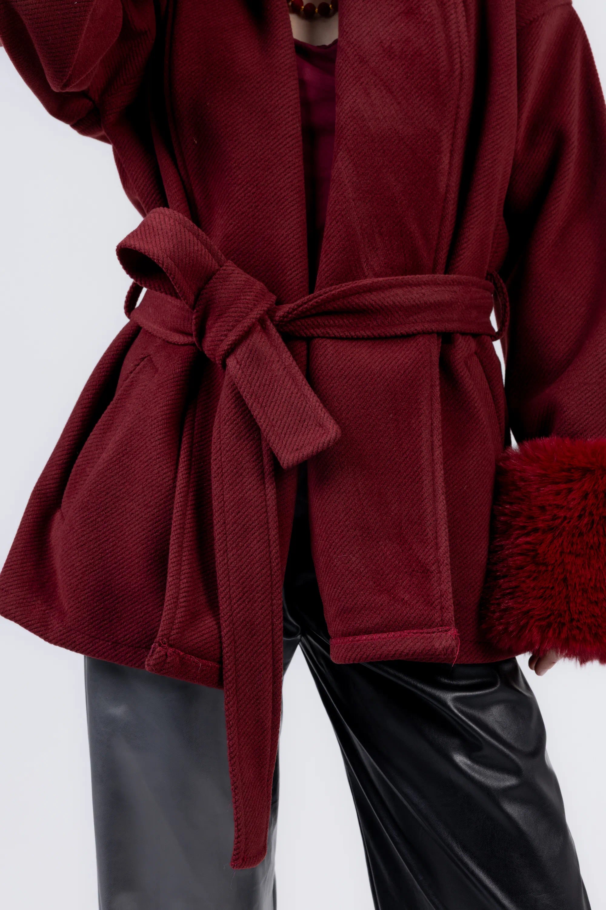 Red coat with a belt and black pants on a white background