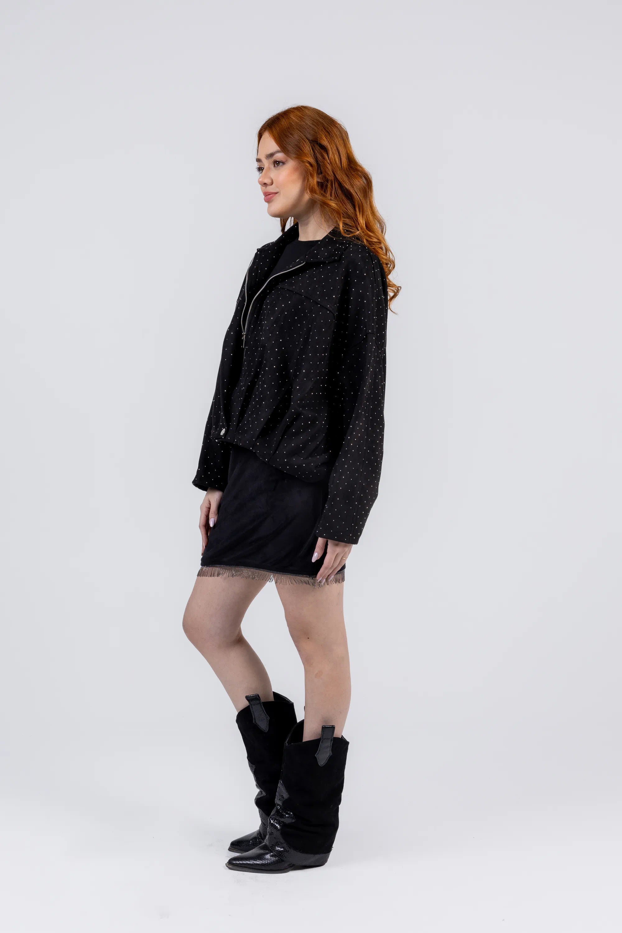 Woman wearing a black textured jacket, dress, and boots on a white background
