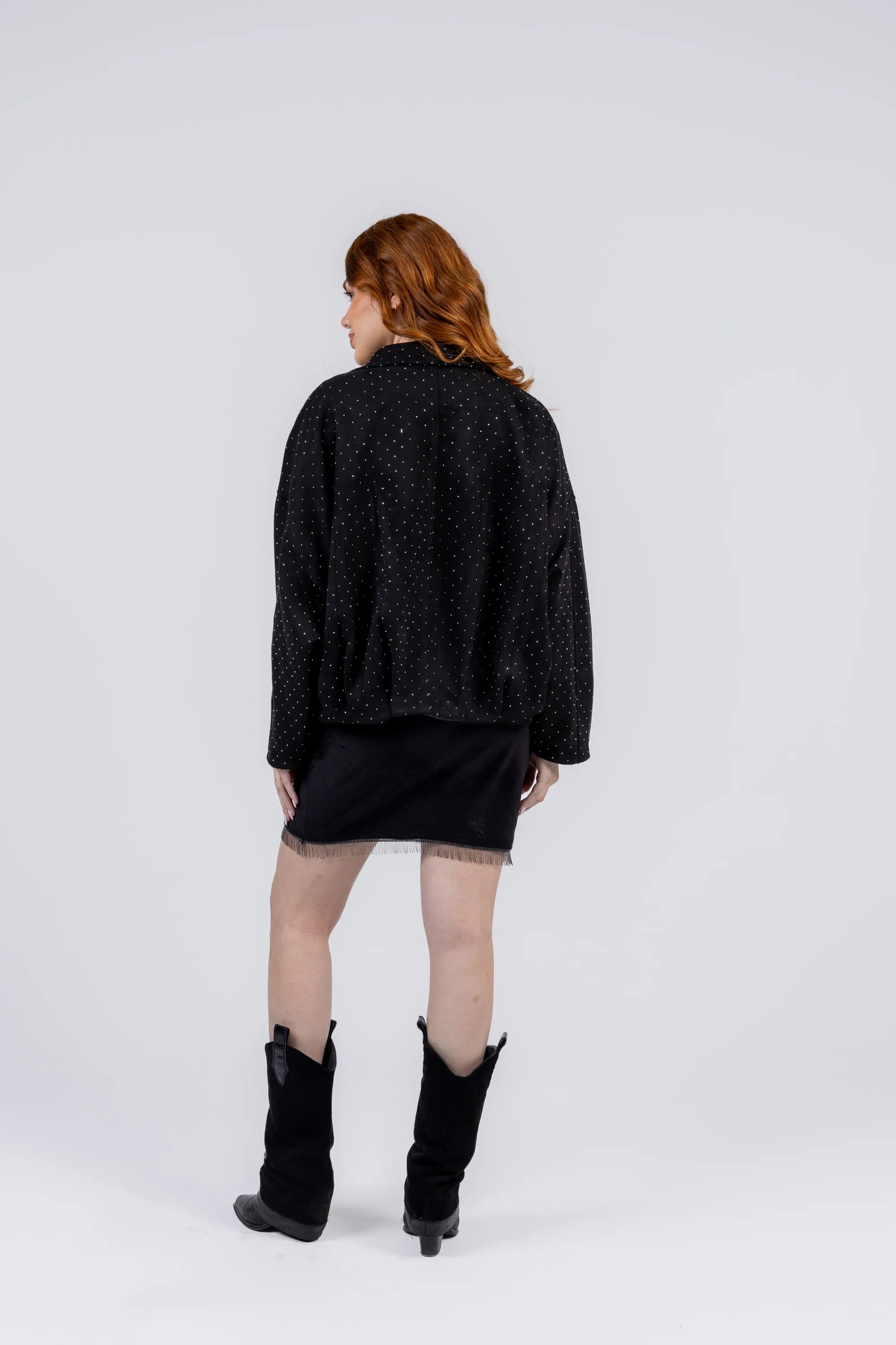Person wearing a black textured sweater and black boots on a white background