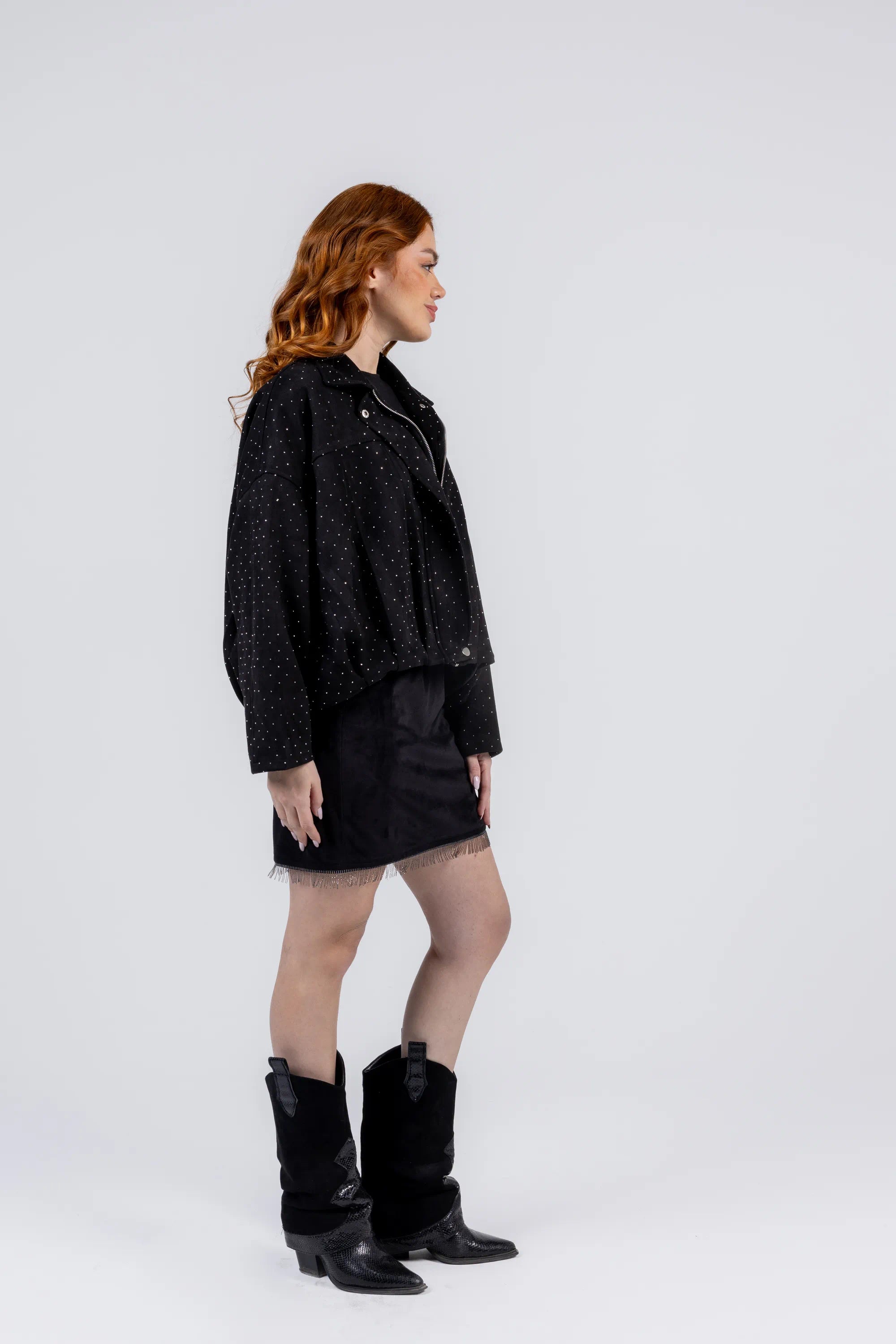 Woman wearing a black jacket, skirt, and boots on a white background