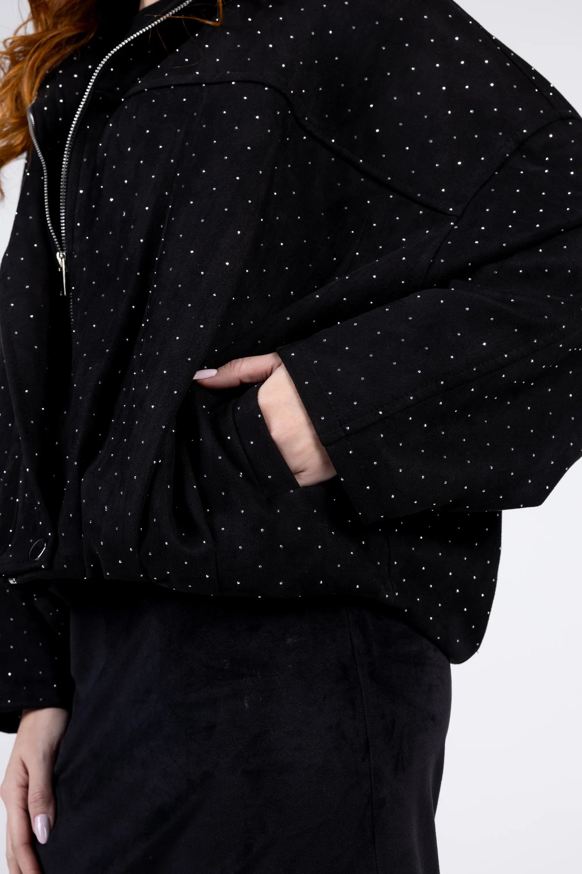 Person wearing a black jacket with white polka dots on a plain background