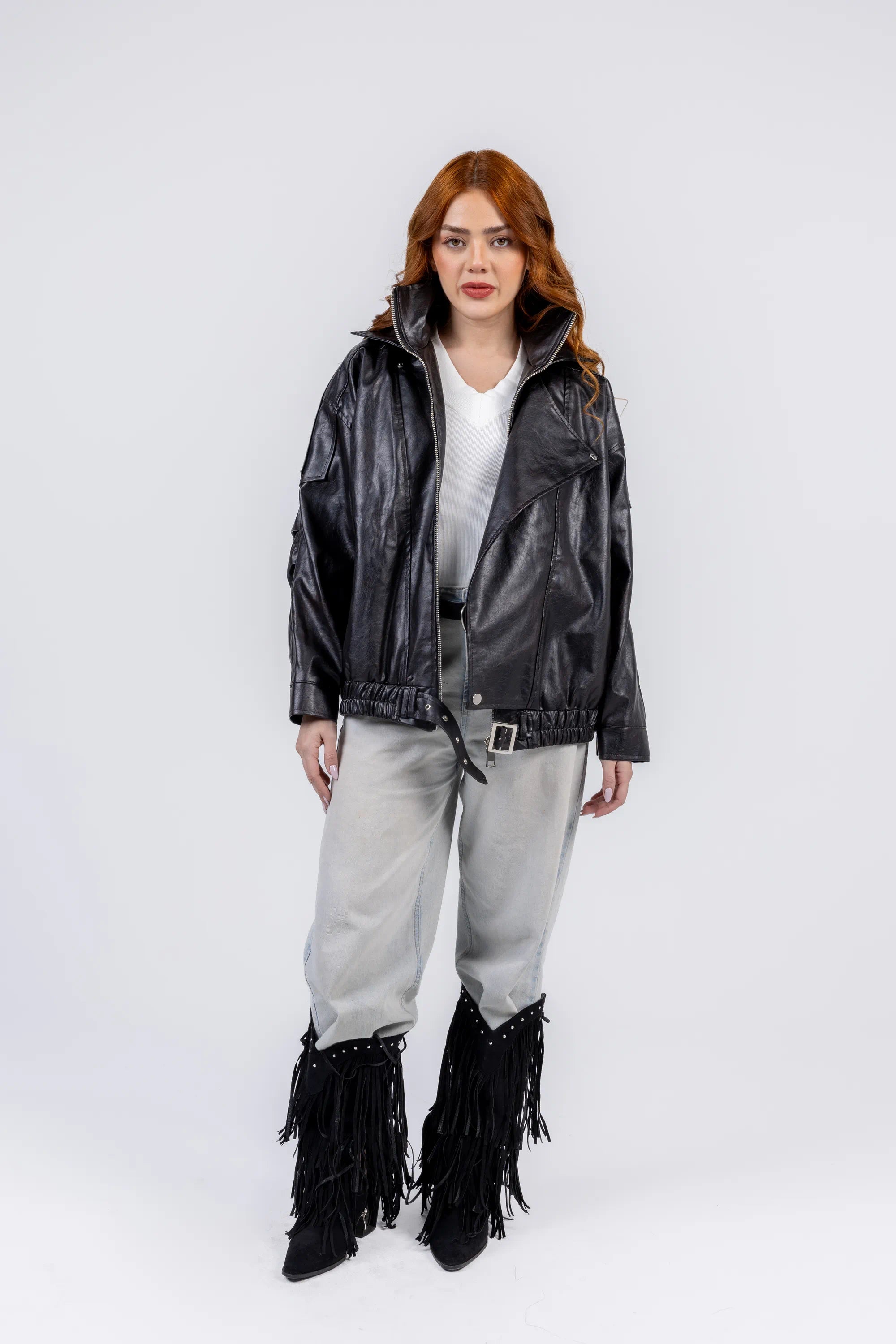 Person wearing a black leather jacket with fringe details on a white background