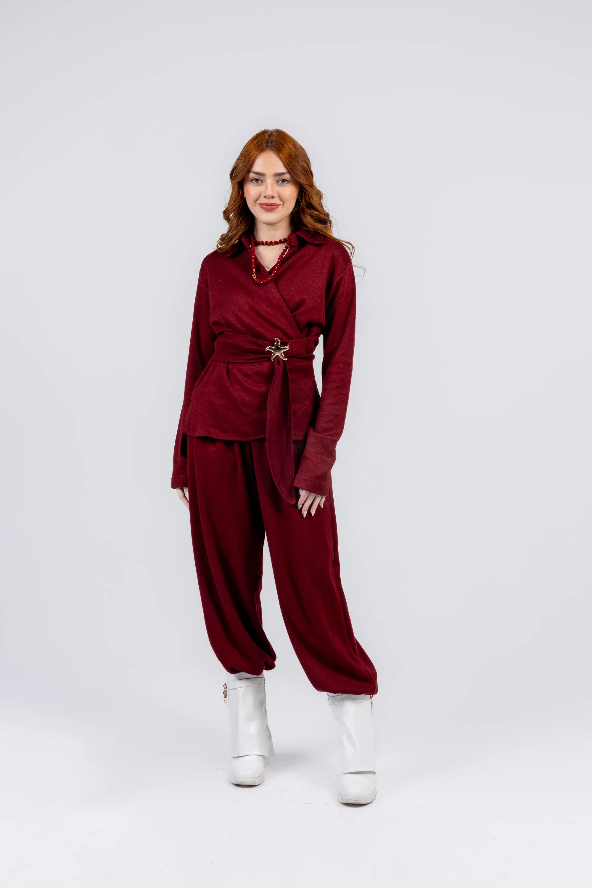 Woman wearing a burgundy outfit with a belt on a white background