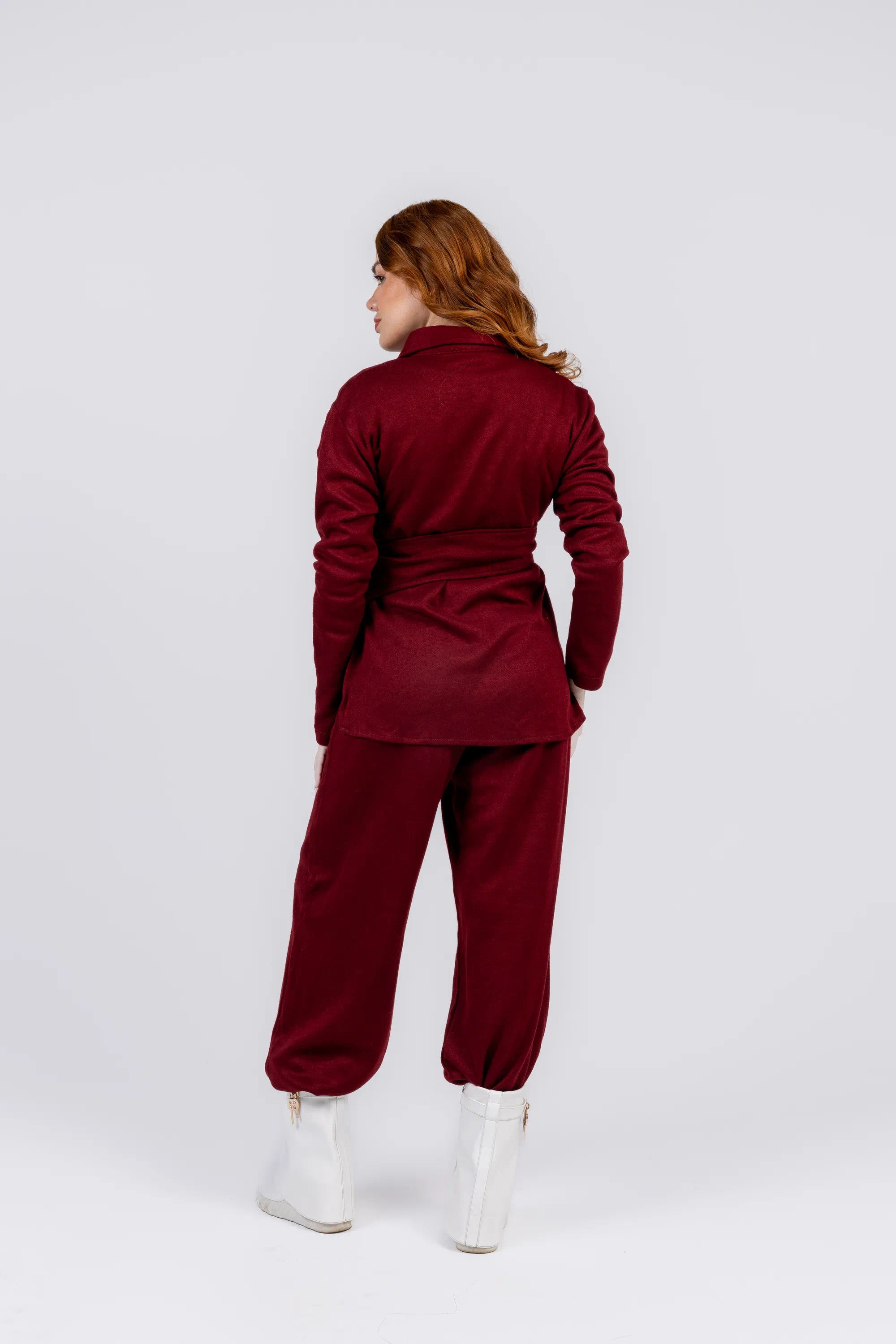 Person wearing a burgundy tracksuit on a white background