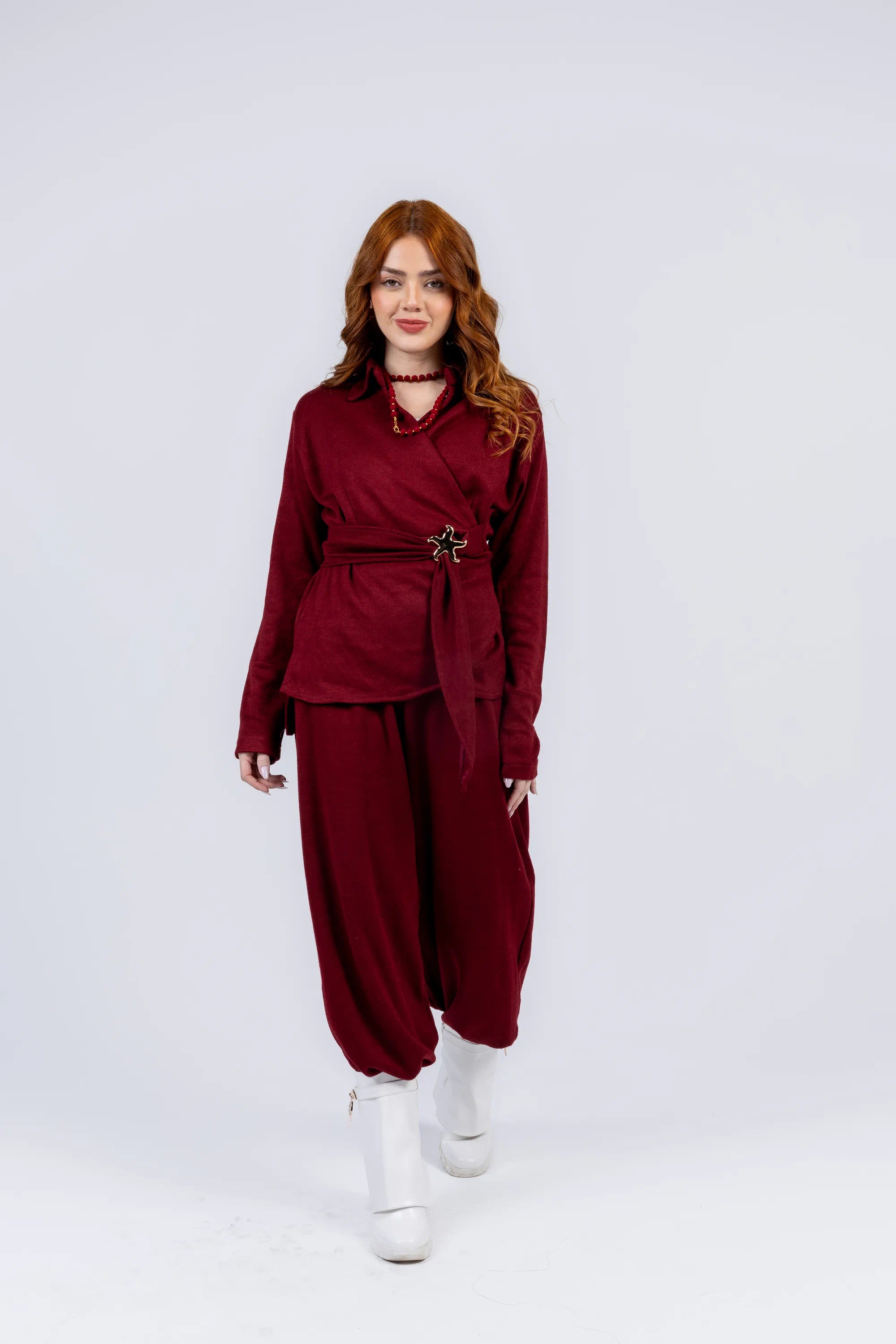 Woman wearing a burgundy outfit with a belt on a white background