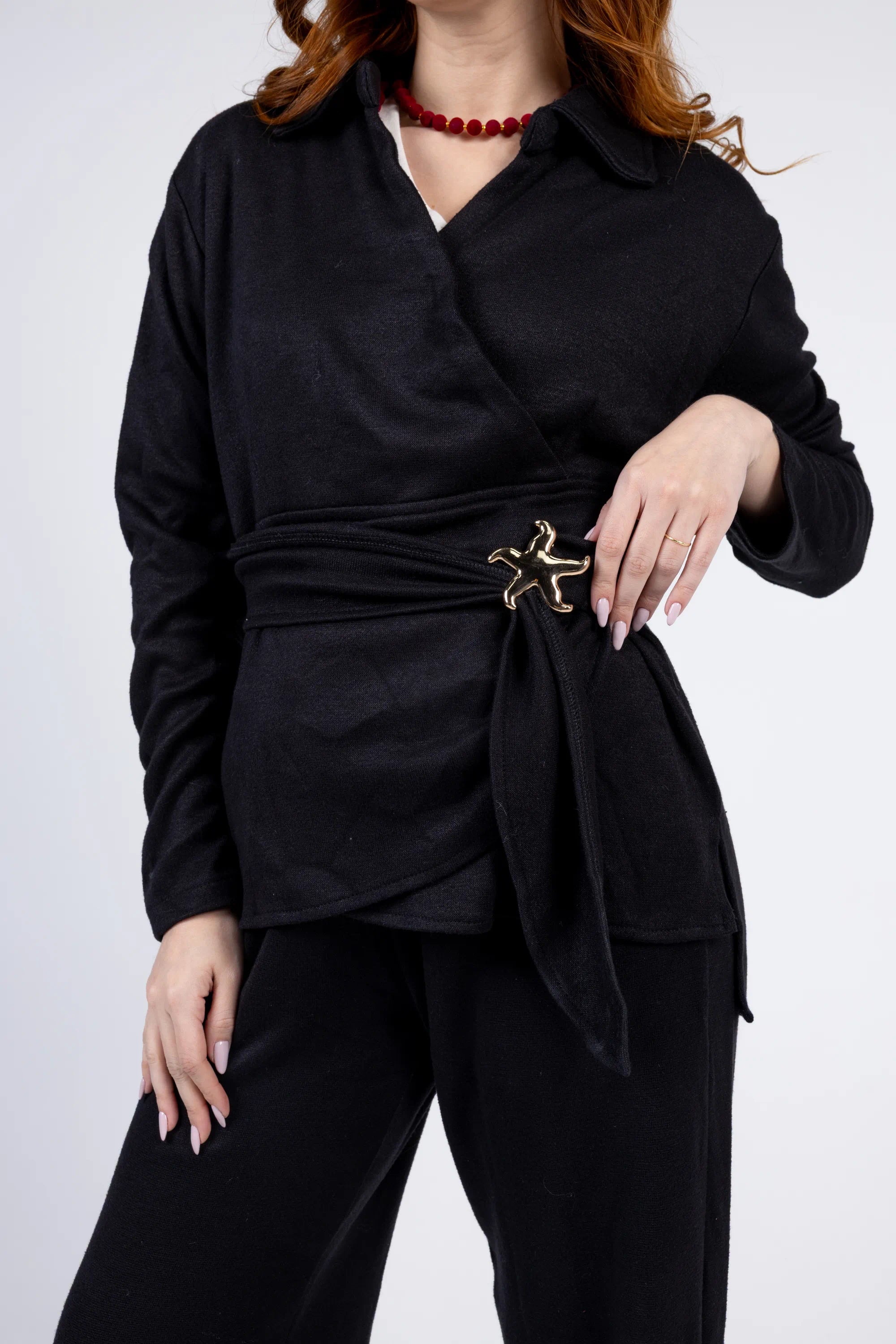 Person wearing a black outfit with a belt and a white background