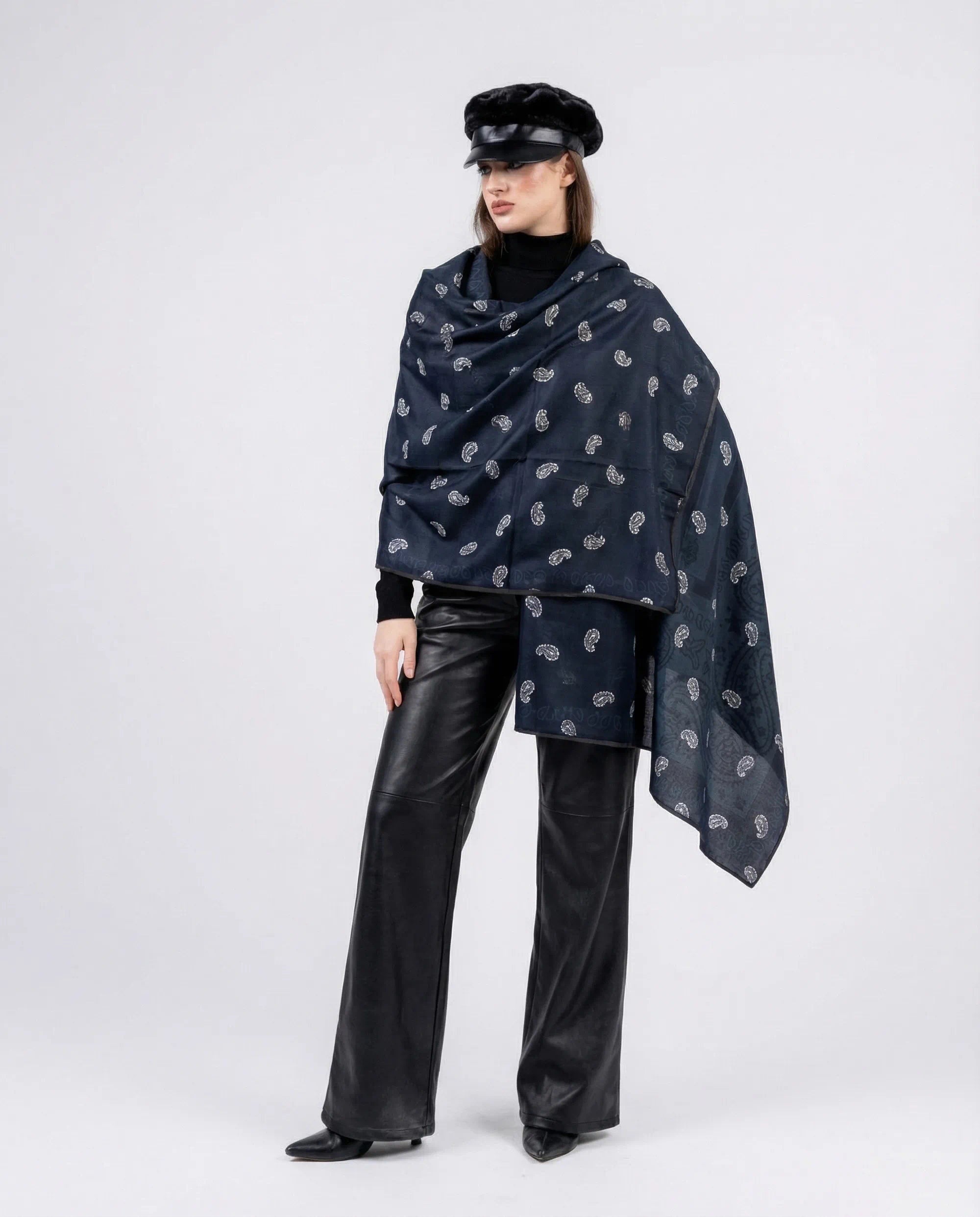 Person wearing a dark blue patterned shawl over a black outfit on a white background