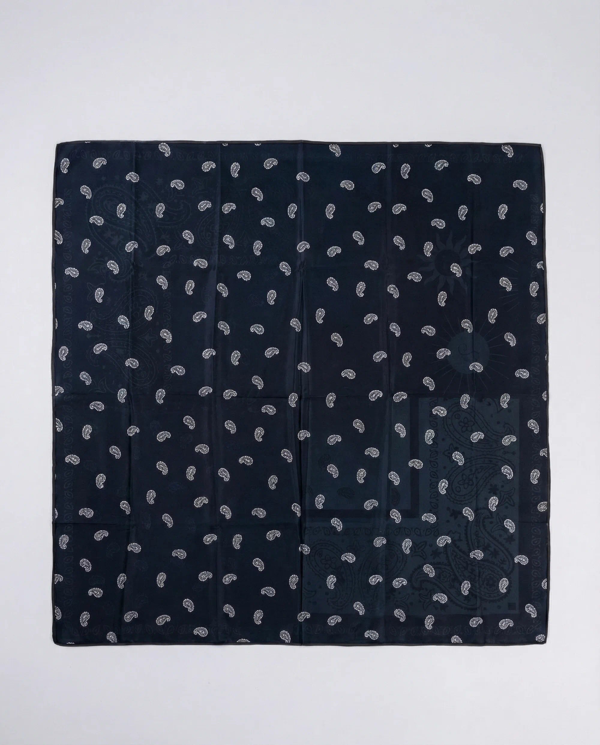 Navy blue pocket square with white paisley pattern on a light gray background
