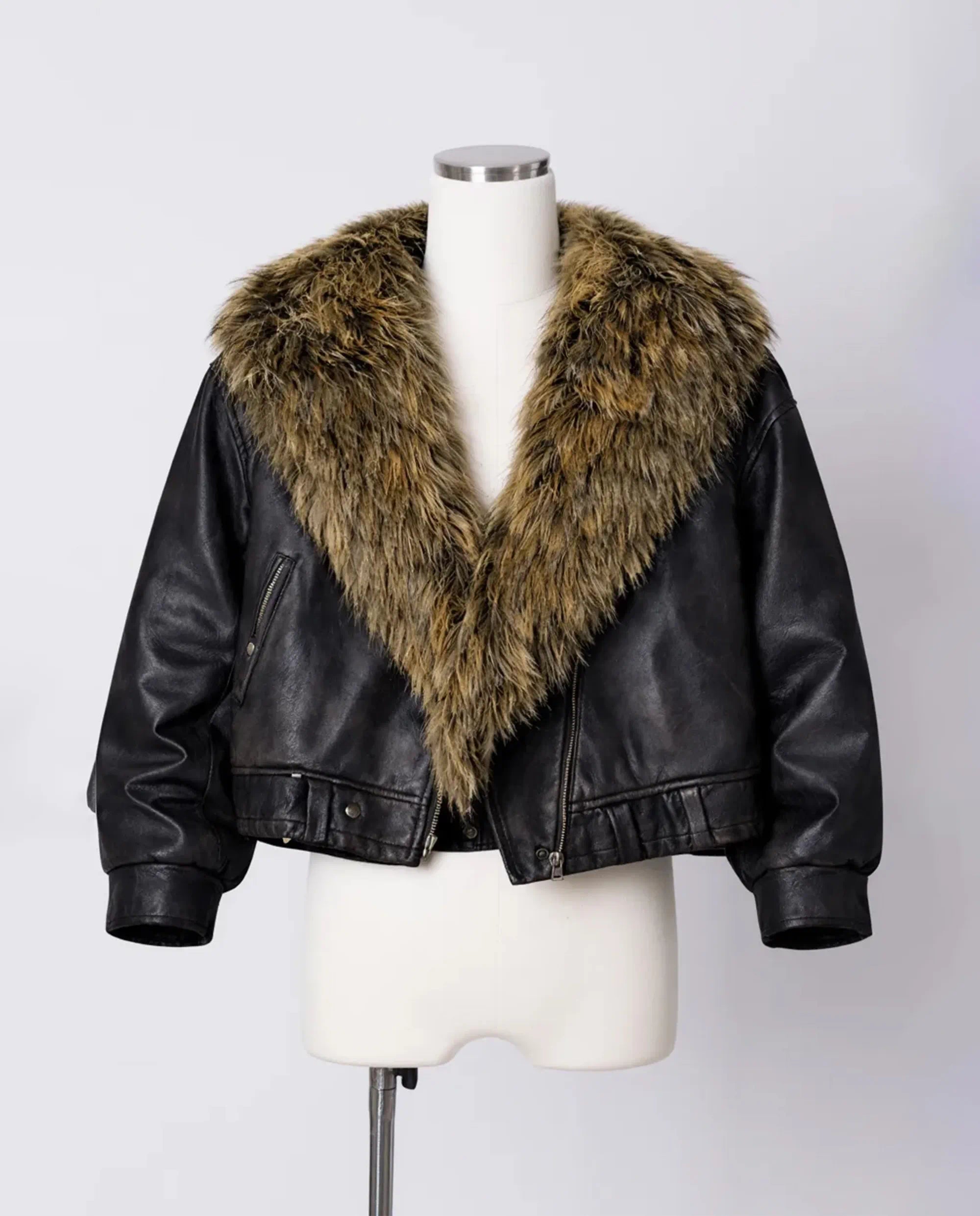 Black leather jacket with fur collar on a mannequin against a white background