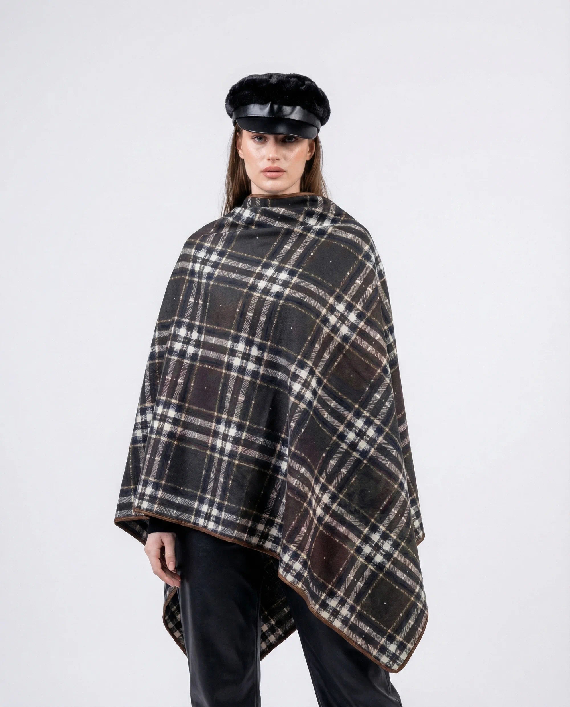 Person wearing a plaid poncho and black cap on a white background